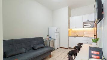 Un espacio habitable compacto con sofá, una pequeña mesa de comedor y una kitchenette.