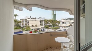 Ein Balkon mit weißem Tisch und Stühlen, Blick auf die Stadtlandschaft und ein Gebäude mit gewölbter Decke.