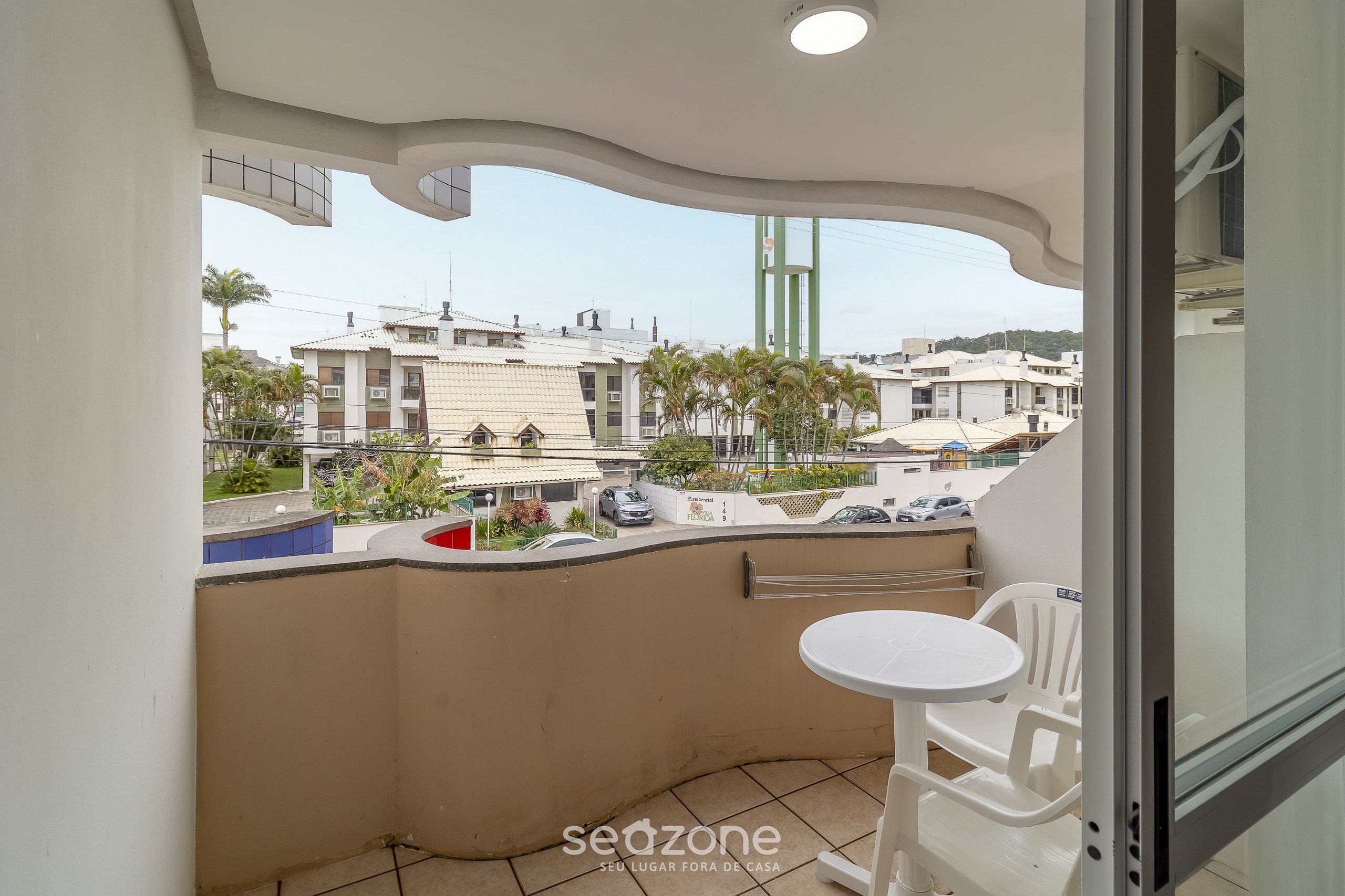 A balcony with a white table and chairs, a view of the cityscape, and a building with a curved ceiling.