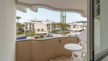 A balcony with a white table and chairs, a view of the cityscape, and a building with a curved ceiling.