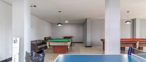 A recreational room with a pool table, billiards tables, and a seating area.