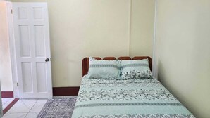 A bedroom with a bed, a door, and an air conditioning unit.