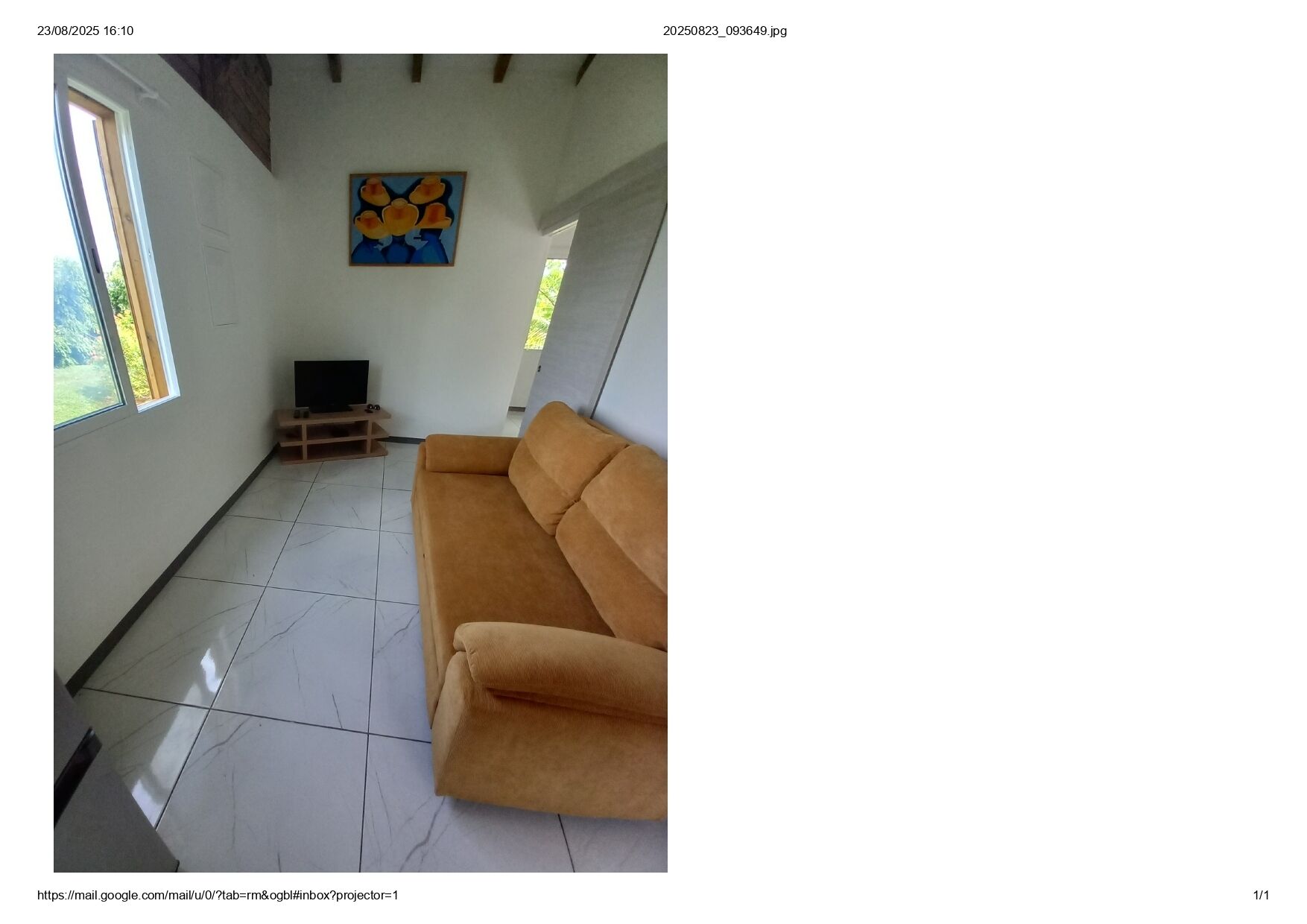 Une pièce spacieuse avec une grande fenêtre, un canapé et un tableau accroché au mur.