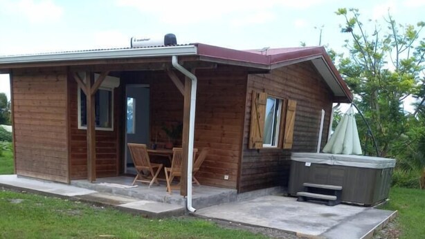 Una cabaña de madera con un porche, un jacuzzi y una pequeña mesa y sillas.