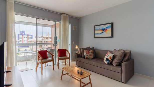 Una sala de estar moderna con un sofá, dos sillones, una mesa de centro y un televisor.