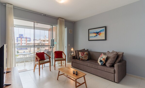 A modern living room with a sofa, two chairs, a coffee table, and a TV.