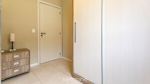 Ein Zimmer mit Schrank, Nachttisch mit Lampe und einer Steckdose.