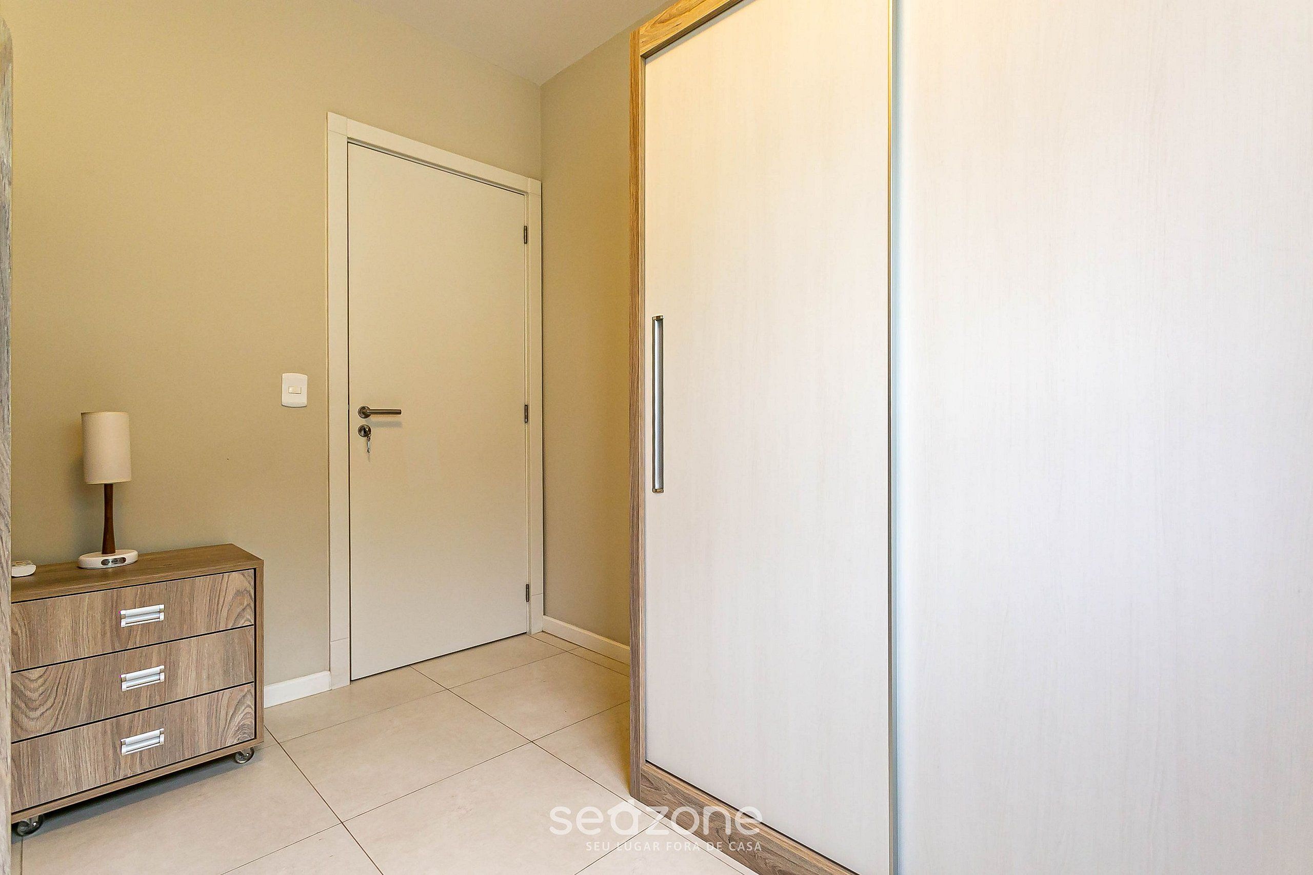Un couloir avec une commode en bois, une porte blanche et une armoire.