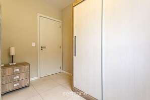 A hallway with a wooden dresser, a white door, and a wardrobe. - Comfortable Apart 400 m From the Beach Idp104 (Florianópolis)