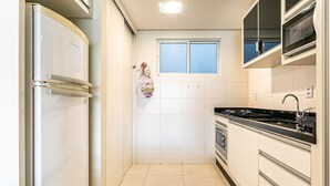 Eine kleine Küche mit Kühlschrank, Backofen und Mikrowelle.
