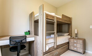 Quarto com beliche, escrivaninha, cadeira e mesa de cabeceira com gavetas.