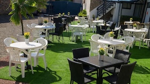 An outdoor patio with tables and chairs, some with umbrellas, and a staircase in the background. - Hotel la Baie Royale (Pontorson)