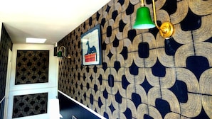 A hallway with patterned wallpaper, a framed picture, and wall-mounted lamps. - Hotel la Baie Royale (Pontorson)