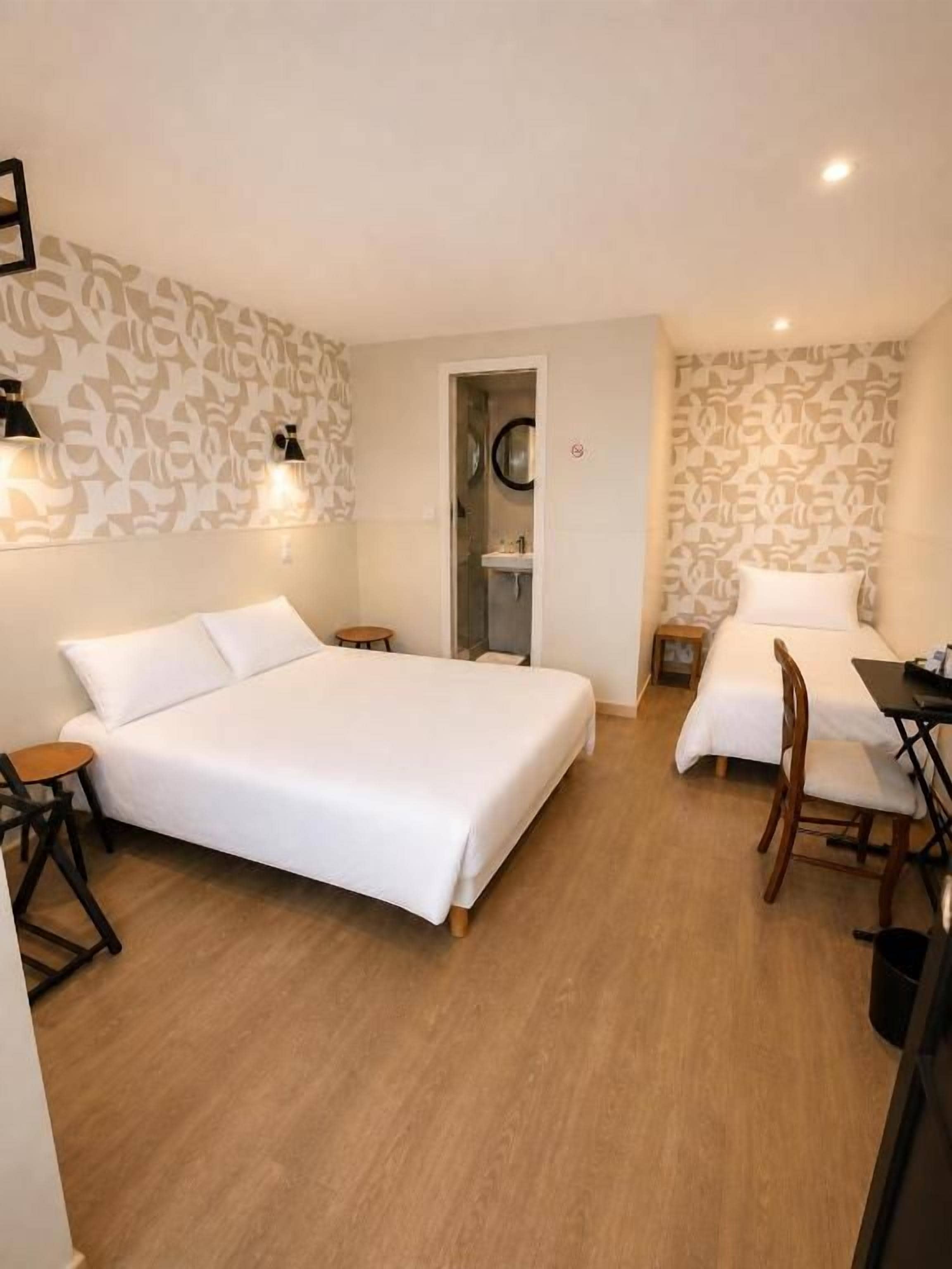 Ett hotellrum med en stor säng, ett skrivbord med en stol, ett litet bord och en spegel.