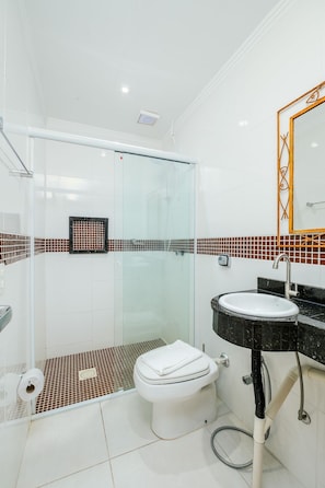 A modern bathroom with a glass shower enclosure, a white toilet, and a black sink with a marble countertop.