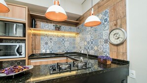 A modern kitchen with a black countertop, stainless steel appliances, and a decorative backsplash. - Apart Foot on Sand for Couples in Floripa Ida105 (Florianópolis)