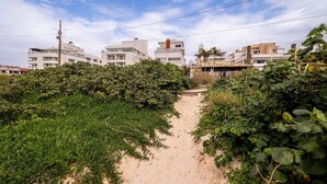 A sandy path leading to a building with multiple floors and balconies, surrounded by dense greenery. - Apart Foot on Sand for Couples in Floripa Ida105 (Florianópolis)