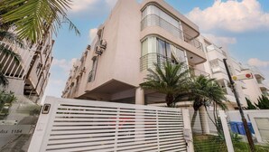 A modern building with a curved facade, balconies, and a gated entrance. - Apart Foot on Sand for Couples in Floripa Ida105 (Florianópolis)