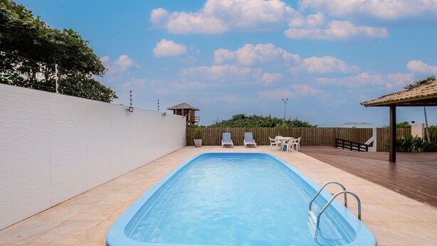 A rectangular swimming pool with a blue interior, surrounded by a tiled deck. - Apart Foot on Sand for Couples in Floripa Ida105 (Florianópolis)