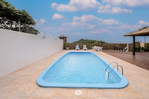 Piscina rectangular con interior azul, rodeada por un solárium con baldosas.