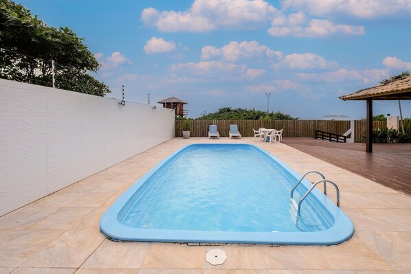 A rectangular swimming pool with a blue interior, surrounded by a tiled deck.