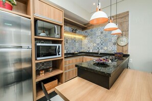 A modern kitchen with built-in appliances, wooden cabinets, and a tiled backsplash. - Apart Foot on Sand for Couples in Floripa Ida105 (Florianópolis)