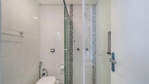 A bathroom with a toilet, a glass shower enclosure, and tiled walls. - Excellent Beachfront apt With Barbecue Ida101 (Florianópolis)