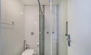 A modern bathroom with a glass-enclosed shower, a toilet, and a small trash bin. - Excellent Beachfront apt With Barbecue Ida101 (Florianópolis)