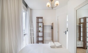 A modern bedroom with a large bed, a wooden ladder shelf, a walk-in closet, and a bathroom with a shower and toilet. - Excellent Beachfront apt With Barbecue Ida101 (Florianópolis)