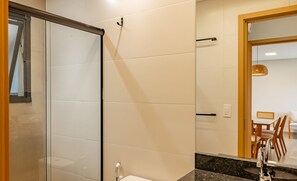 Une salle de bain moderne avec une douche à parois de verre, un comptoir en marbre et un lavabo avec un robinet.