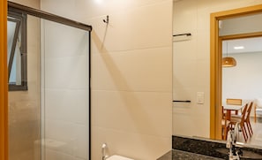 Une salle de bain moderne avec une douche à parois de verre, un comptoir en marbre et un lavabo avec un robinet.