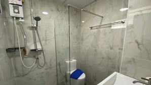 Un baño moderno con ducha de vidrio, inodoro blanco y lavabo con espejo.