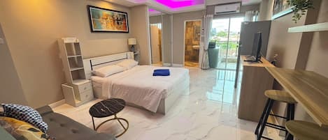 A modern bedroom with a bed, bedside tables, a desk, and a chair.
