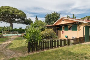 Eine Villa mit Swimmingpool, Holzzaun und einem großen Baum.