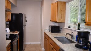 A kitchen with a refrigerator, microwave, sink, and wooden cabinets. - Cozy Newly Renovated 3 Bedroom Home 5 min. to SoCo & 15 min. to Zilker Park (Austin)