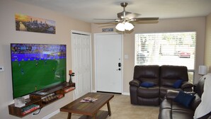 A living room with a television, a brown leather sofa, a coffee table, and a ceiling fan. - Cozy Newly Renovated 3 Bedroom Home 5 min. to SoCo & 15 min. to Zilker Park (Austin)