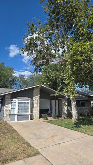 A residential house with a stone facade, a garage, and a tree in the front yard.