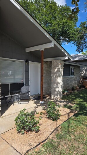 A residential house with a covered porch, a stone pillar, a garage door, and a small garden area.