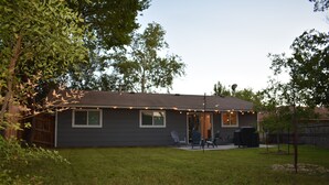 A residential house with a covered patio, a lawn, and a tree in the foreground. - Cozy Newly Renovated 3 Bedroom Home 5 min. to SoCo & 15 min. to Zilker Park (Austin)