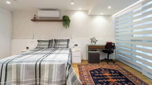 Una camera da letto con un letto, un comodino, una scrivania, una sedia e una finestra con persiane.