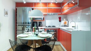 Una cucina moderna con mobili rossi, un'area pranzo con un tavolo rotondo e sedie, e una macchina da caffè in vista.