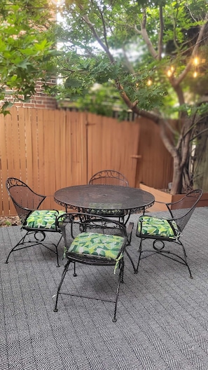 Een terras met een ronde metalen tafel en stoelen, omringd door een vloer met een visgraatmotief.