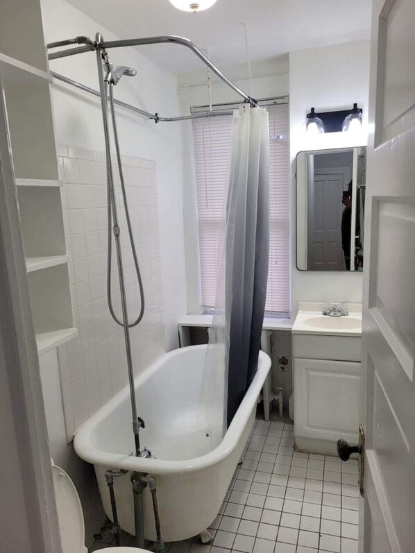 Een badkamer met een wit bad, een douche, een wastafel en een spiegel.