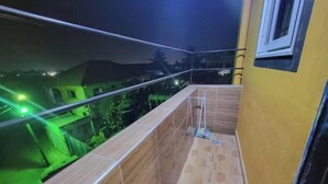 Un balcon donnant sur un quartier résidentiel, de nuit.