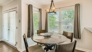 A dining area with a round table, four chairs, and a chandelier. - Holland Heights (Dallas)