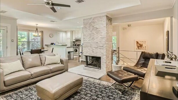 A modern living room with a fireplace, a sofa, a coffee table, and a dining area with a chair. - Holland Heights (Dallas)