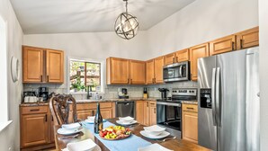 Una cocina moderna con armarios de madera, electrodomésticos de acero inoxidable y una mesa de comedor preparada para seis comensales.