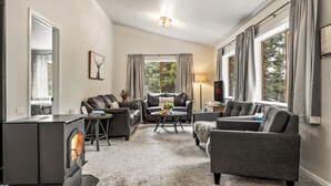 A living room with a fireplace, leather sofas, a coffee table, and a view of the outdoors. - Wayward Lodge- Hot Tub- Fire Pit- Secluded (Divide)