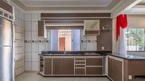 A modern kitchen with built-in cabinets, a stainless steel refrigerator, and a window with a red curtain.