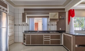 A modern kitchen with built-in appliances, a central island, and a view of the outdoors. - Houses Near Beto Carrero World - REK (Penha)